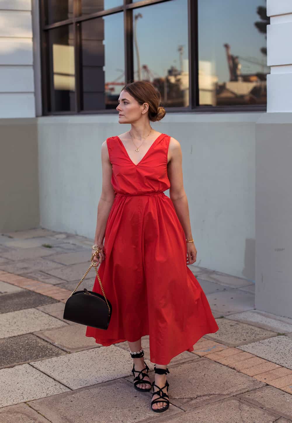 image of a woman in a red midi dress and black sandals walking down the sidewalk