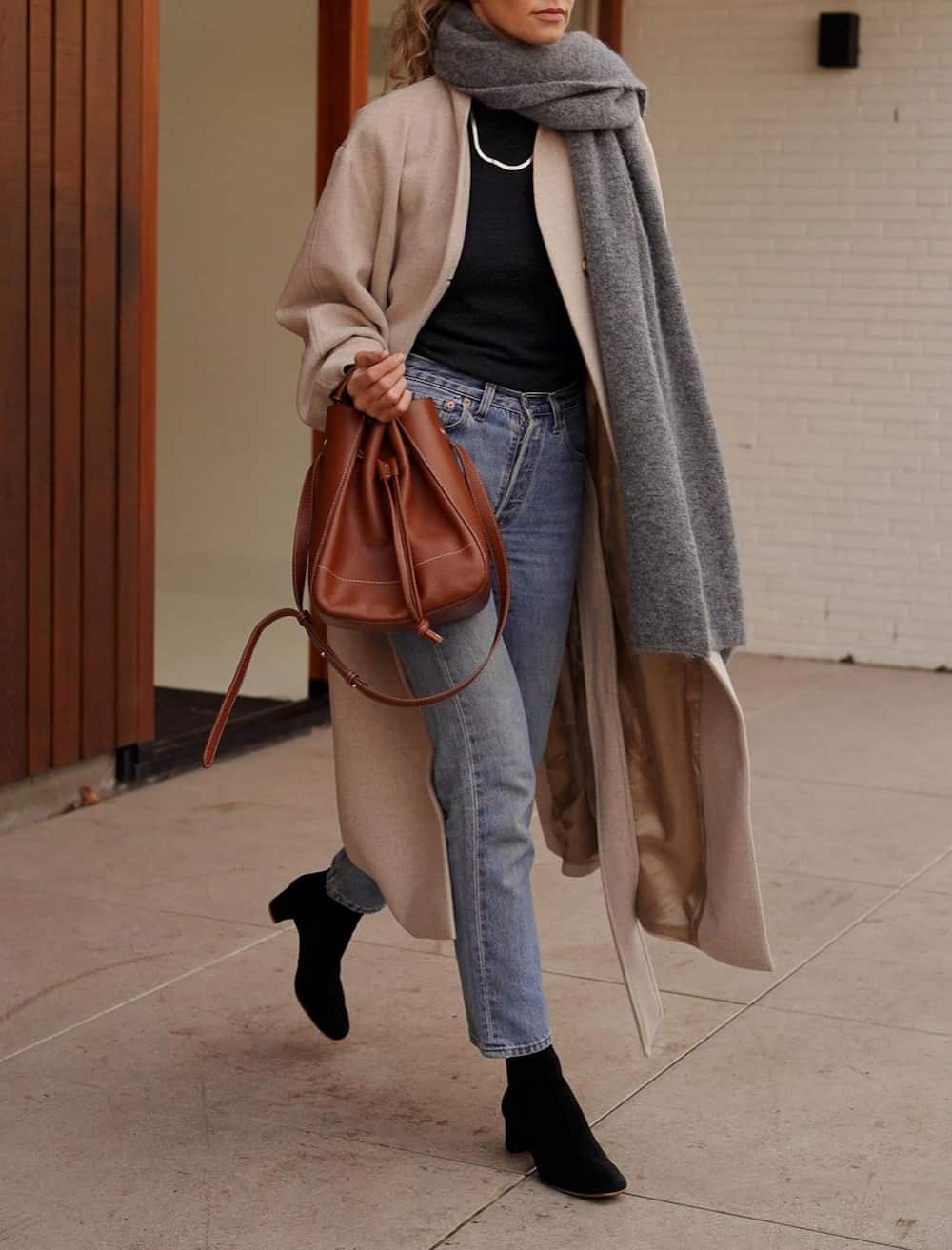 image of a woman in vintage wash jeans, a black sweater, black boots, a wool coat, and long scarf
