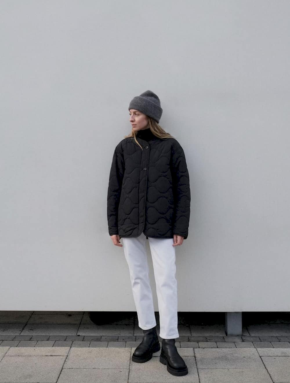 image of a woman in a grey toque, black quilted jacket, white pants, and black lug boots