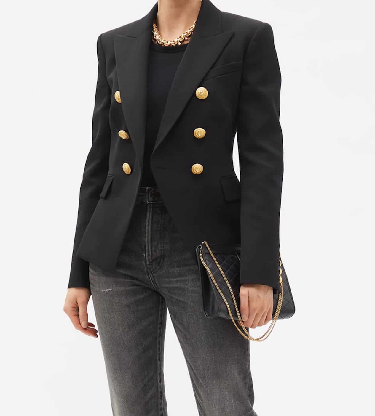 image of a woman wearing a black Balmain blazer with gold buttons and washed black denim jeans