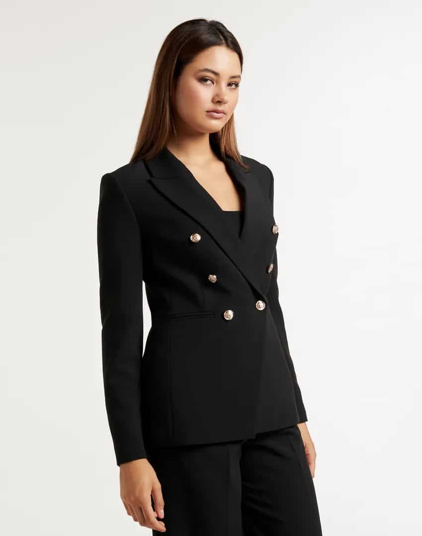 image of a woman wearing a black blazer with gold buttons and tailored black pants