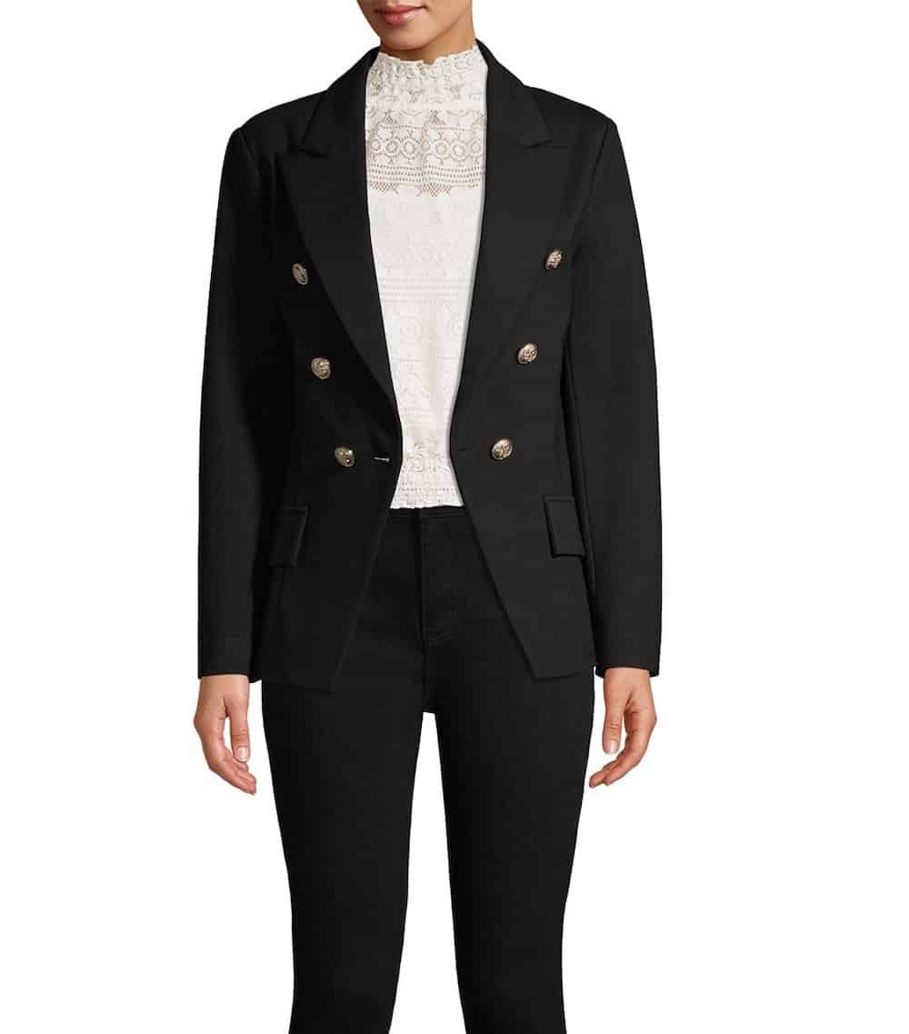 woman wearing a black double-breasted blazer with gold buttons that is a dupe of the Balmain blazer, with a white blouse and black jeans