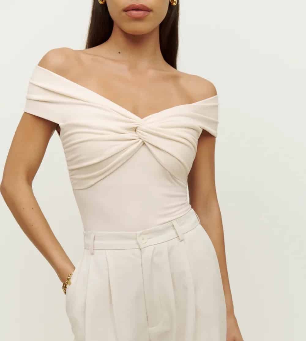 woman wearing an ivory off the shoulder ruched top that is a dupe of the Khaite Cerise bodysuit