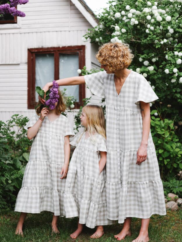 image of a woman with two young girls standing in a garden wearing matching light green gingham dresses