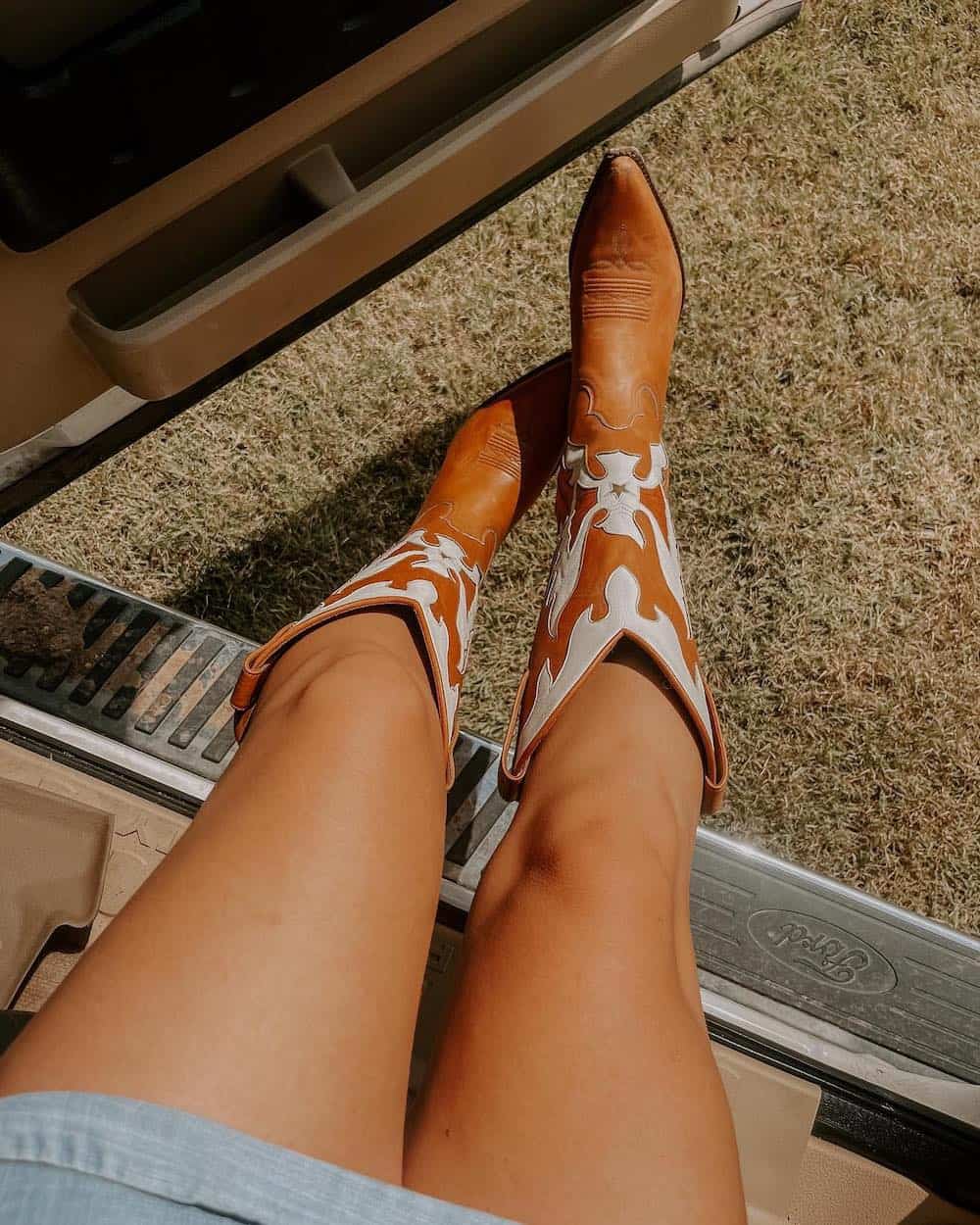image of a woman's legs wearing brown and white cowboy boots for the rodeo