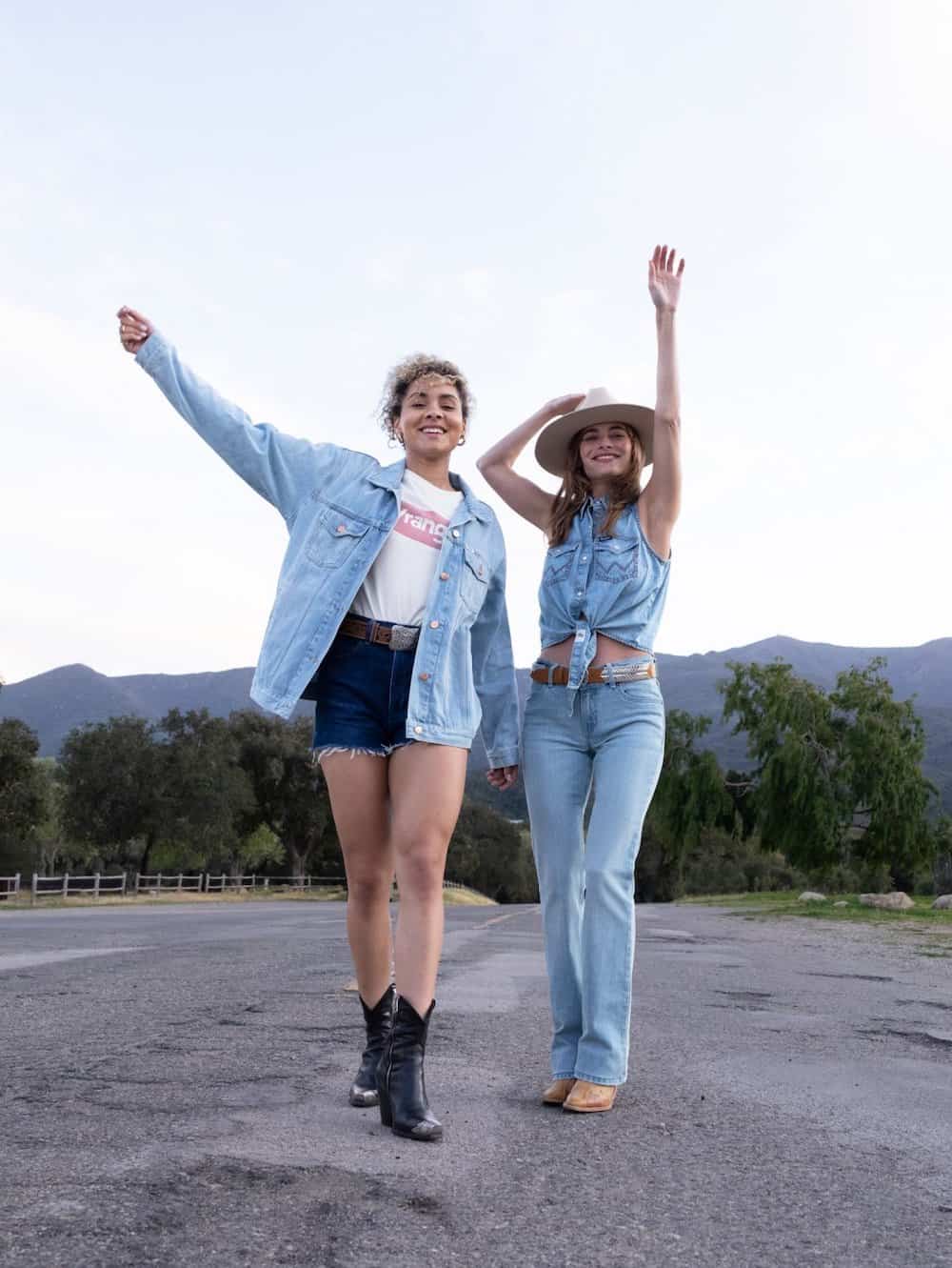Two women wearing cute rodeo outfits with cowboy boots, denim shorts, jeans, denim shorts, and a wrangler top
