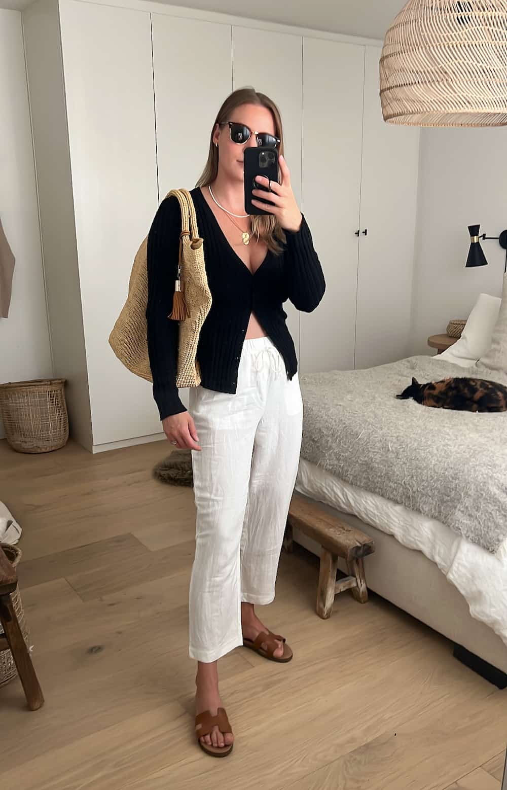 woman wearing a black ribbed cardigan with white linen pants and brown sandals