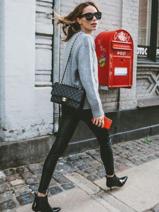 image of a woman walking down the street wearing black leggings, a grey sweater, and a black Chanel purse