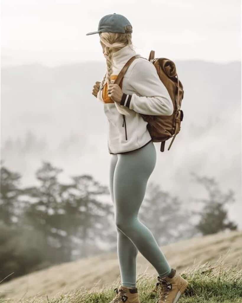 an image of a woman on the top of a mountain wearing hiking attire