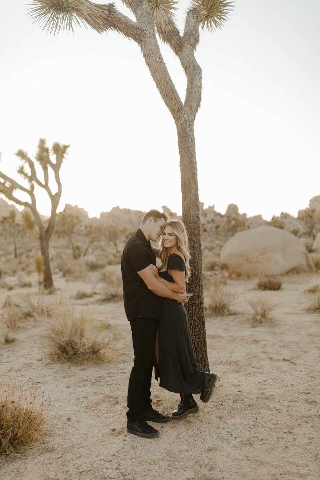 Young man and woman pose in the desert wearing all black.