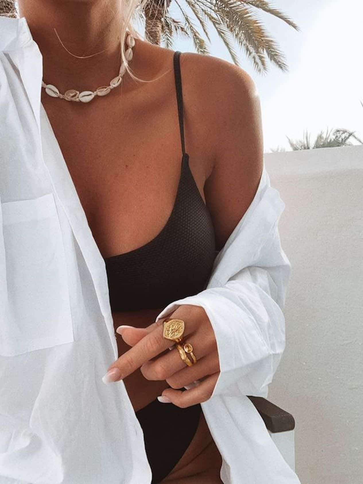 Woman wearing a black bikini and a linen button up coverup.