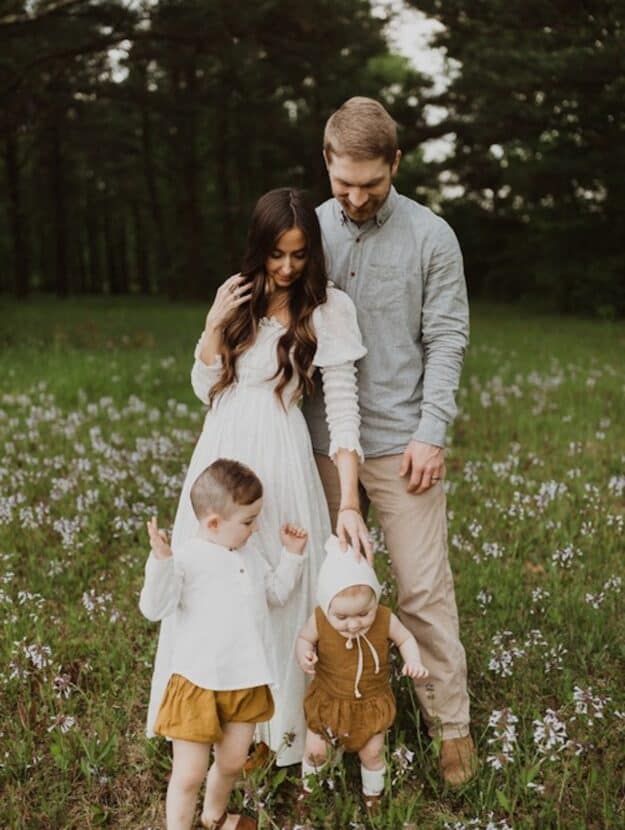 image of a family standing in a field of flowers, the mom wearing a white flowy dress, and the dad in neutrals, and two children wearing matching white and mustard linen clothing