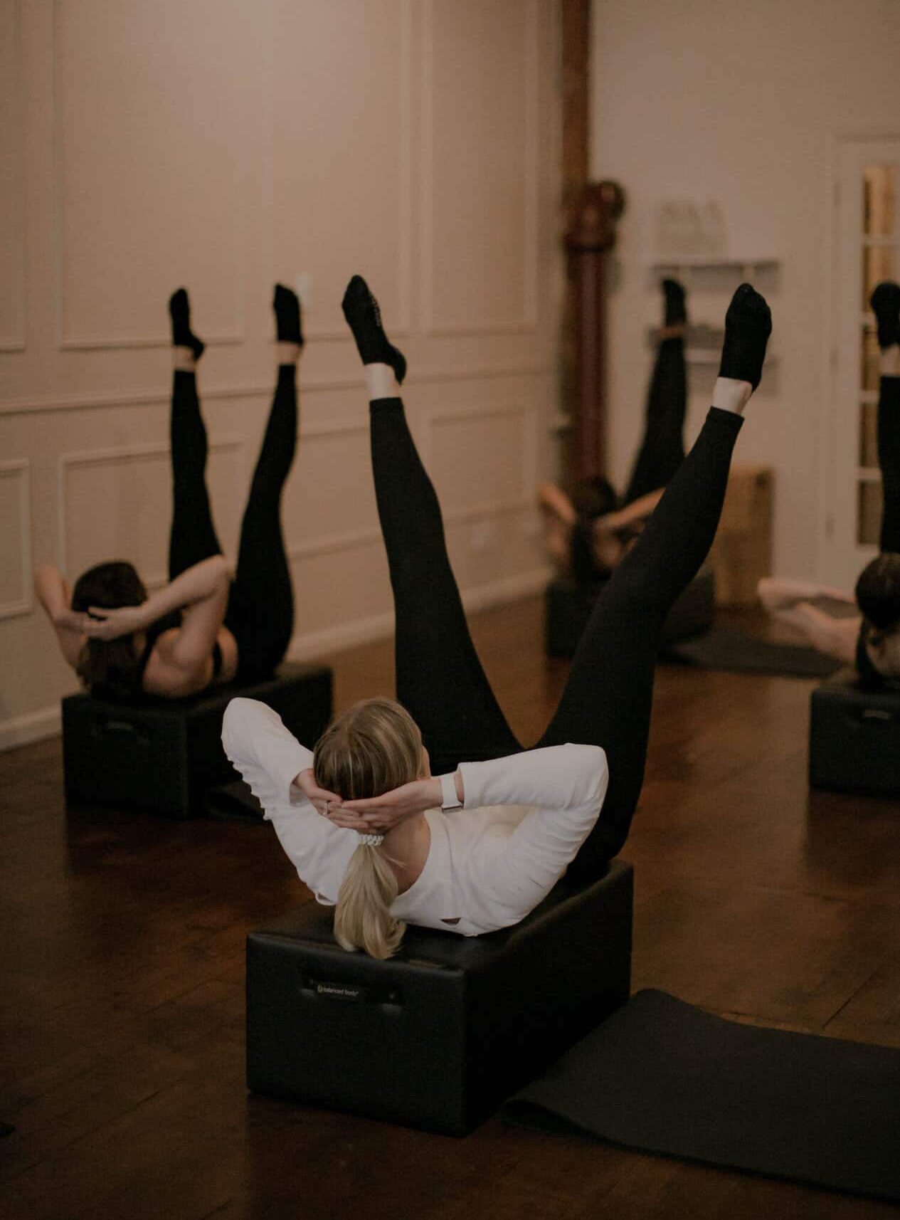 Women on a yoga block with feet in the air during a pilates class