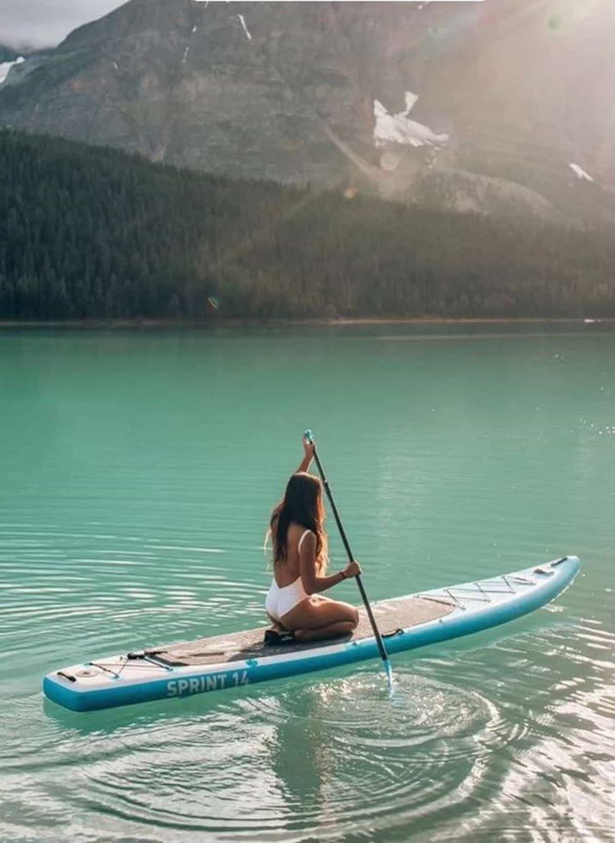 Woman wearing a white one piece swimsuit on a paddle board