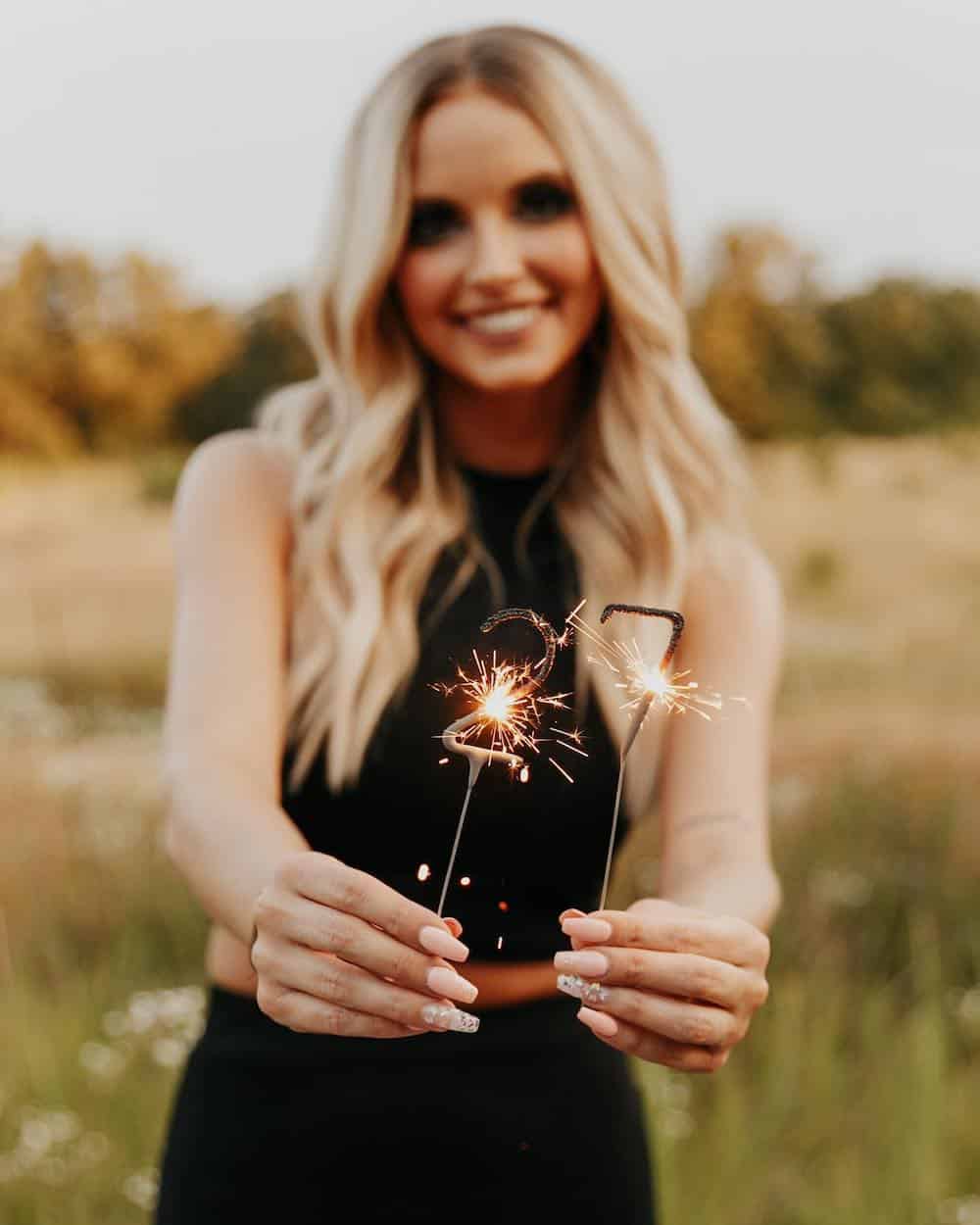 woman holding two sparklers in the number 27 for a birthday photoshoot