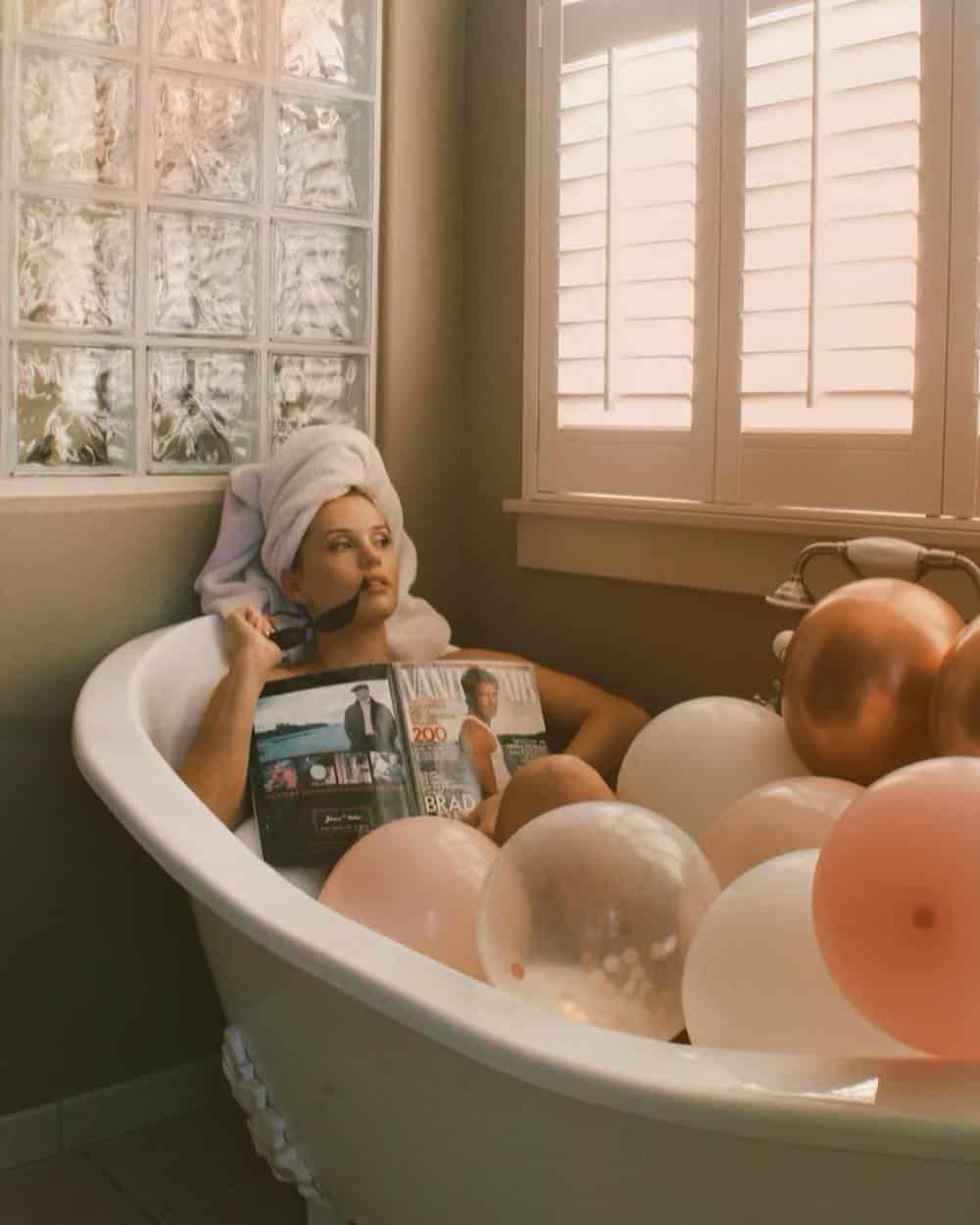 woman having a birthday photoshoot with balloons in a bathtub