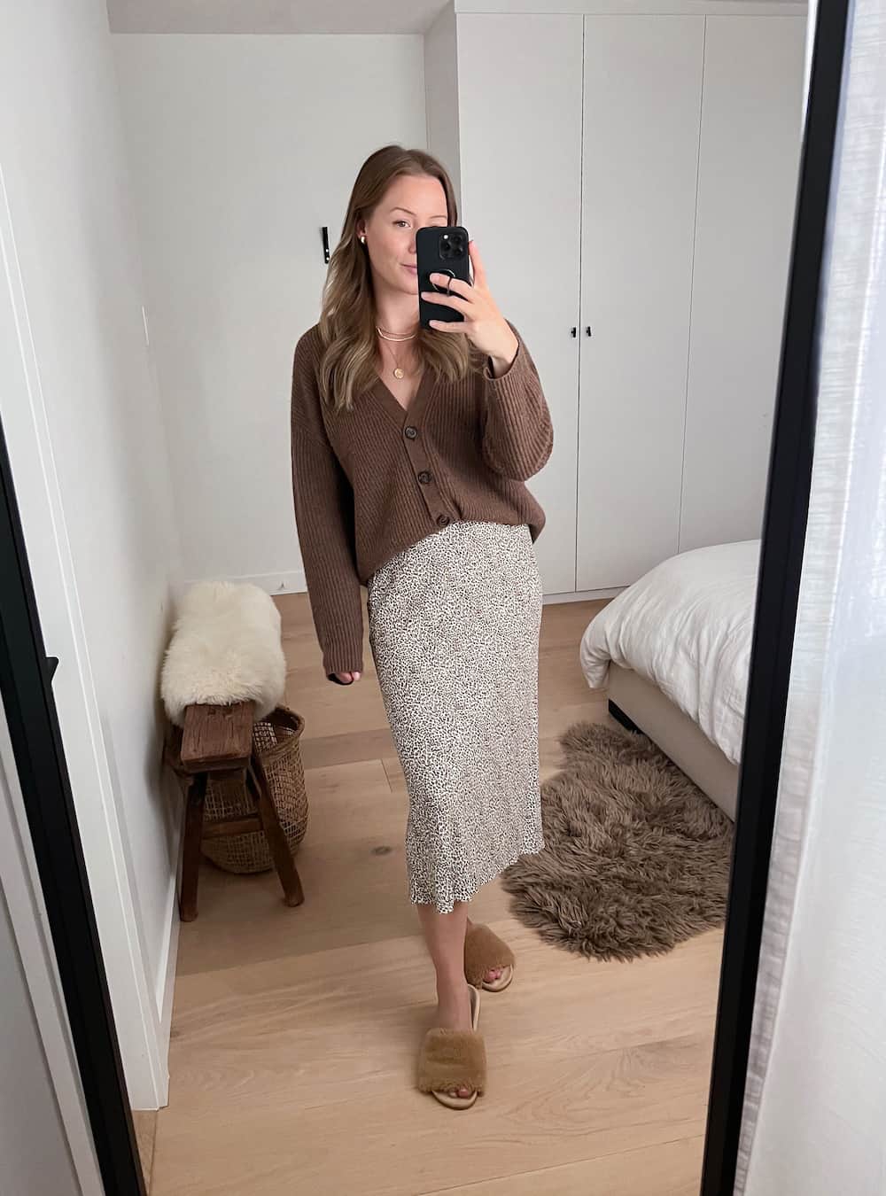 woman wearing a brown cashmere knit cardigan from Jenni Kayne with a leopard midi slip skirt and shearling slides