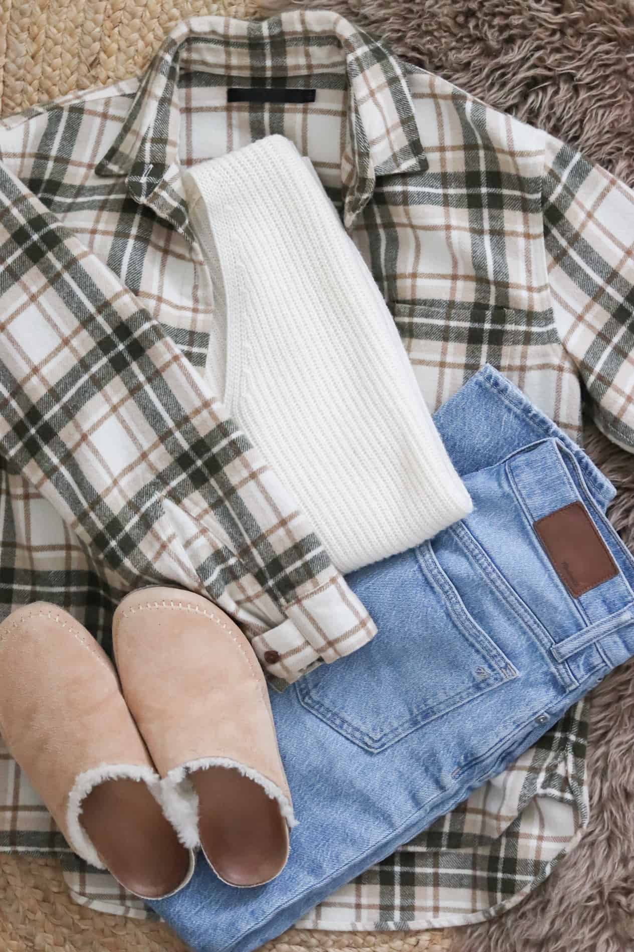Flat lay of a flannel white sweater, jeans and cozy slippers.