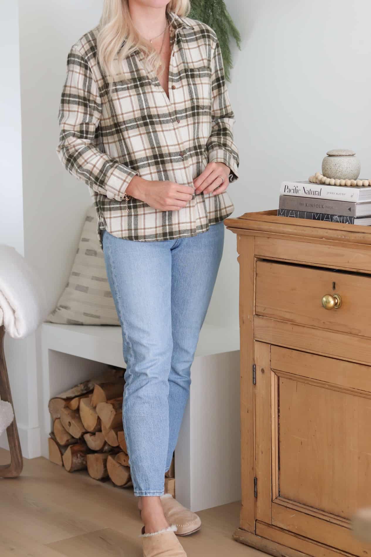 Woman wearing jeans, slippers and a plaid flannel.