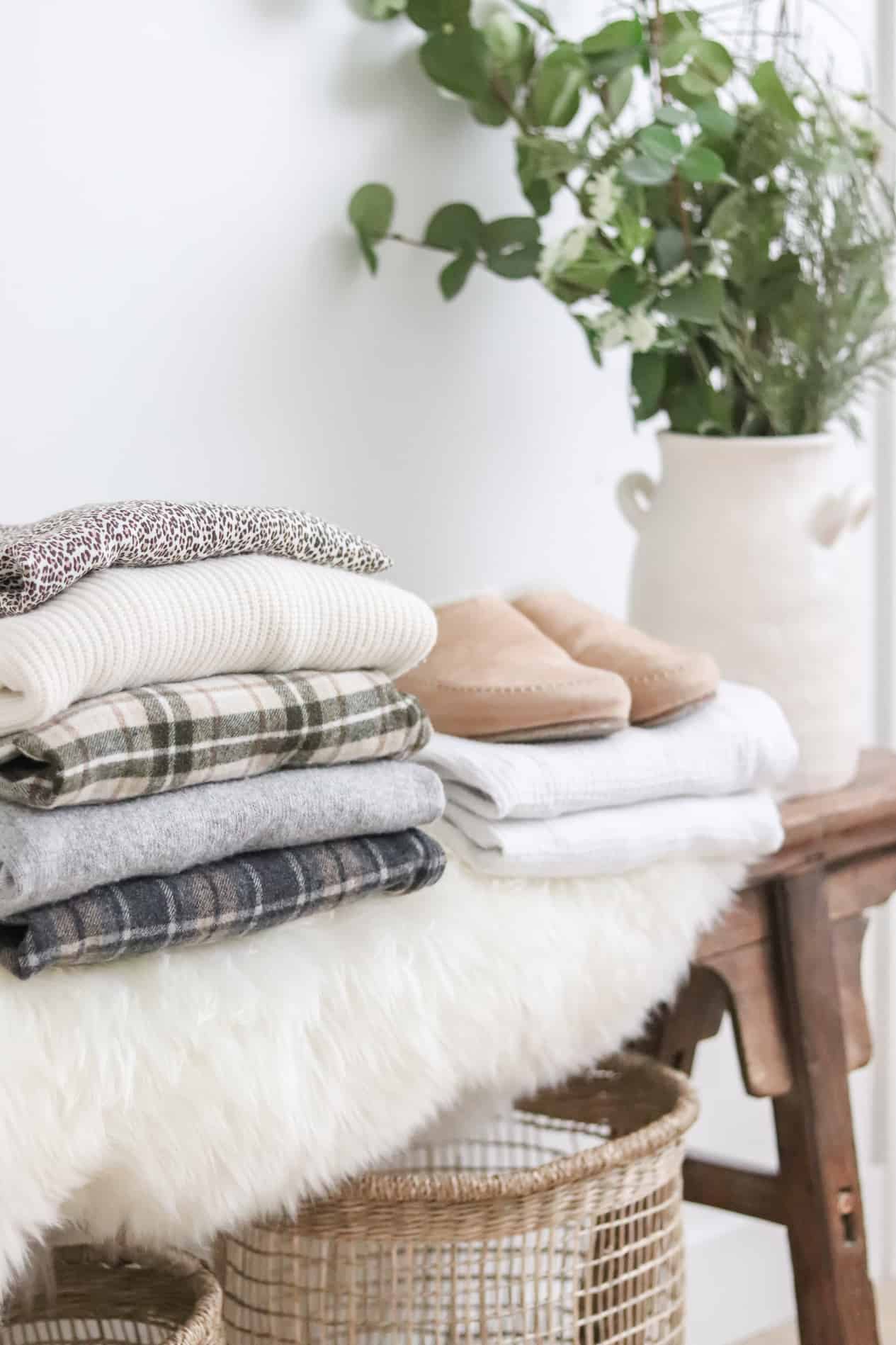 Clothing and slippers stacked on a wooden bench and faux fur.