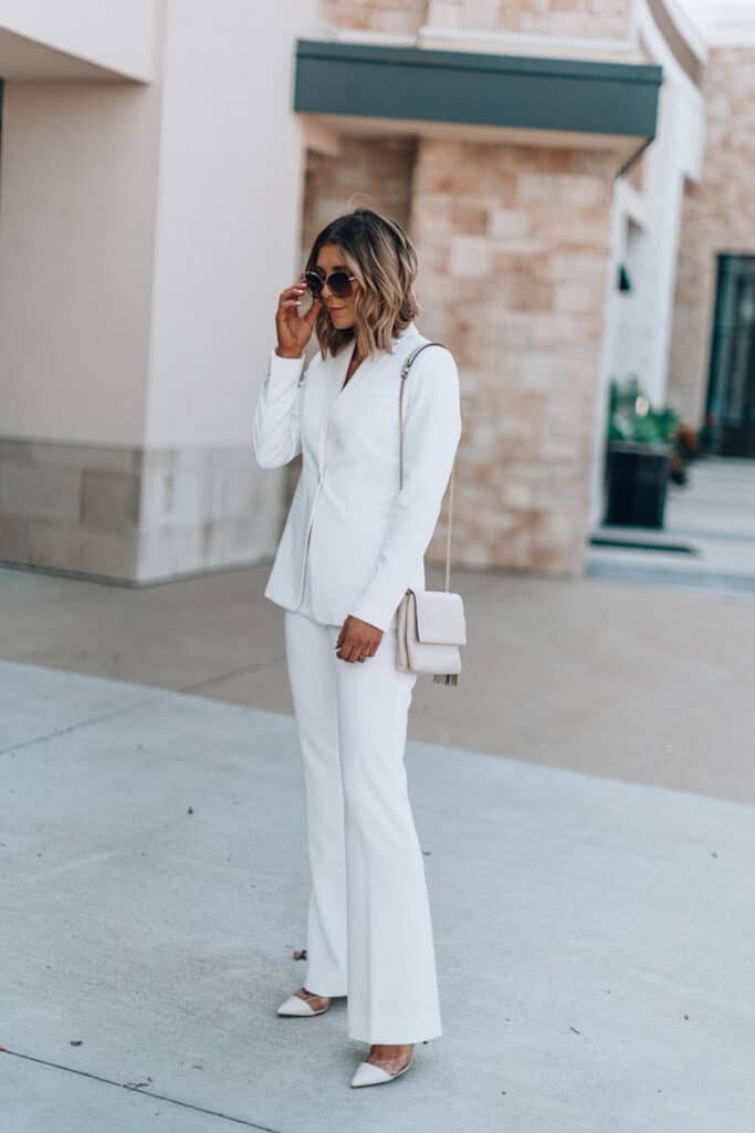 image of a woman standing on a sidewalk wearing a white pantsuit and heels