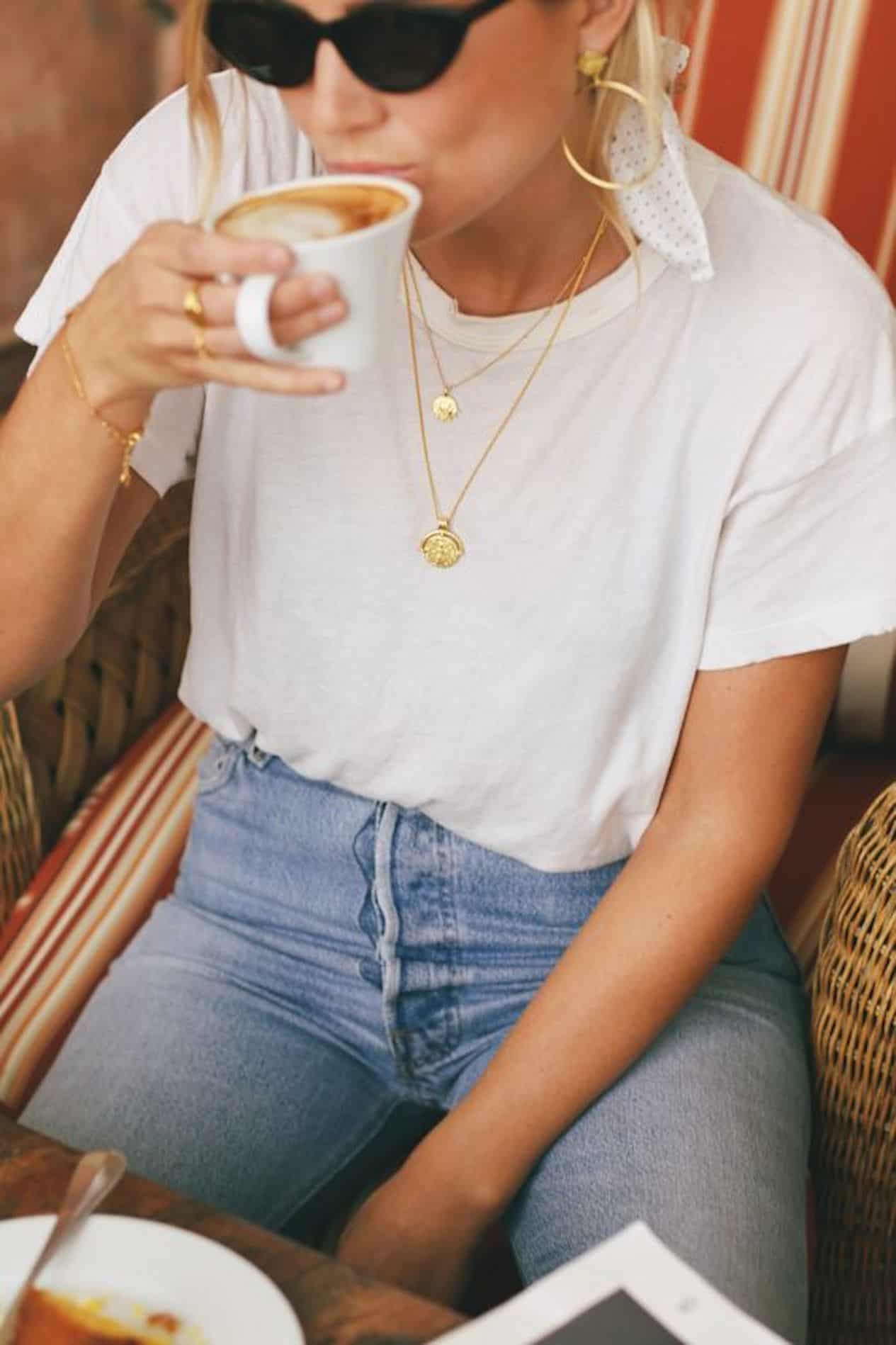image of a woman up close wearing a white t-shirt and layered pendant necklaces