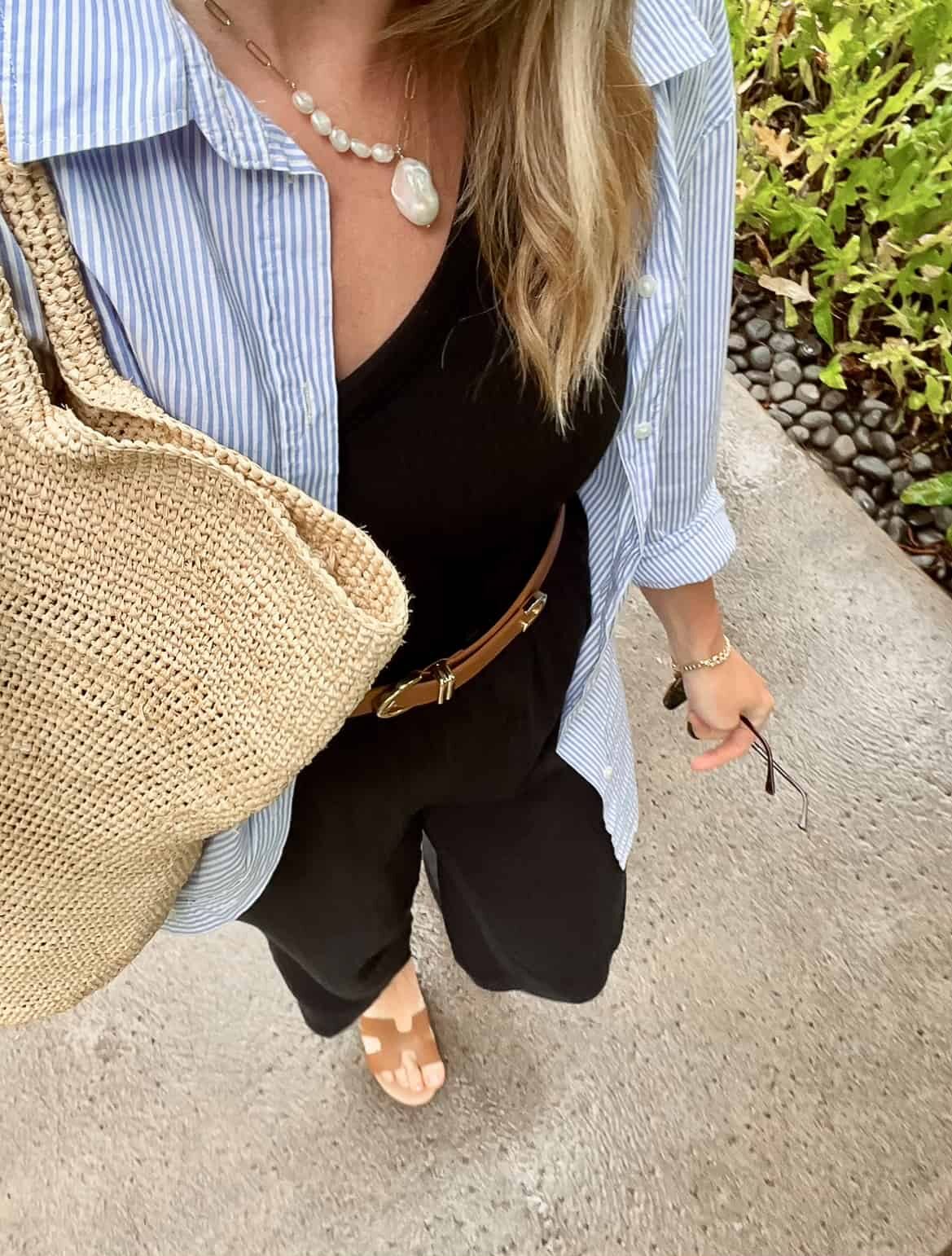 woman wearing a blue striped shirt over a black top with black pants and brown leather sandals