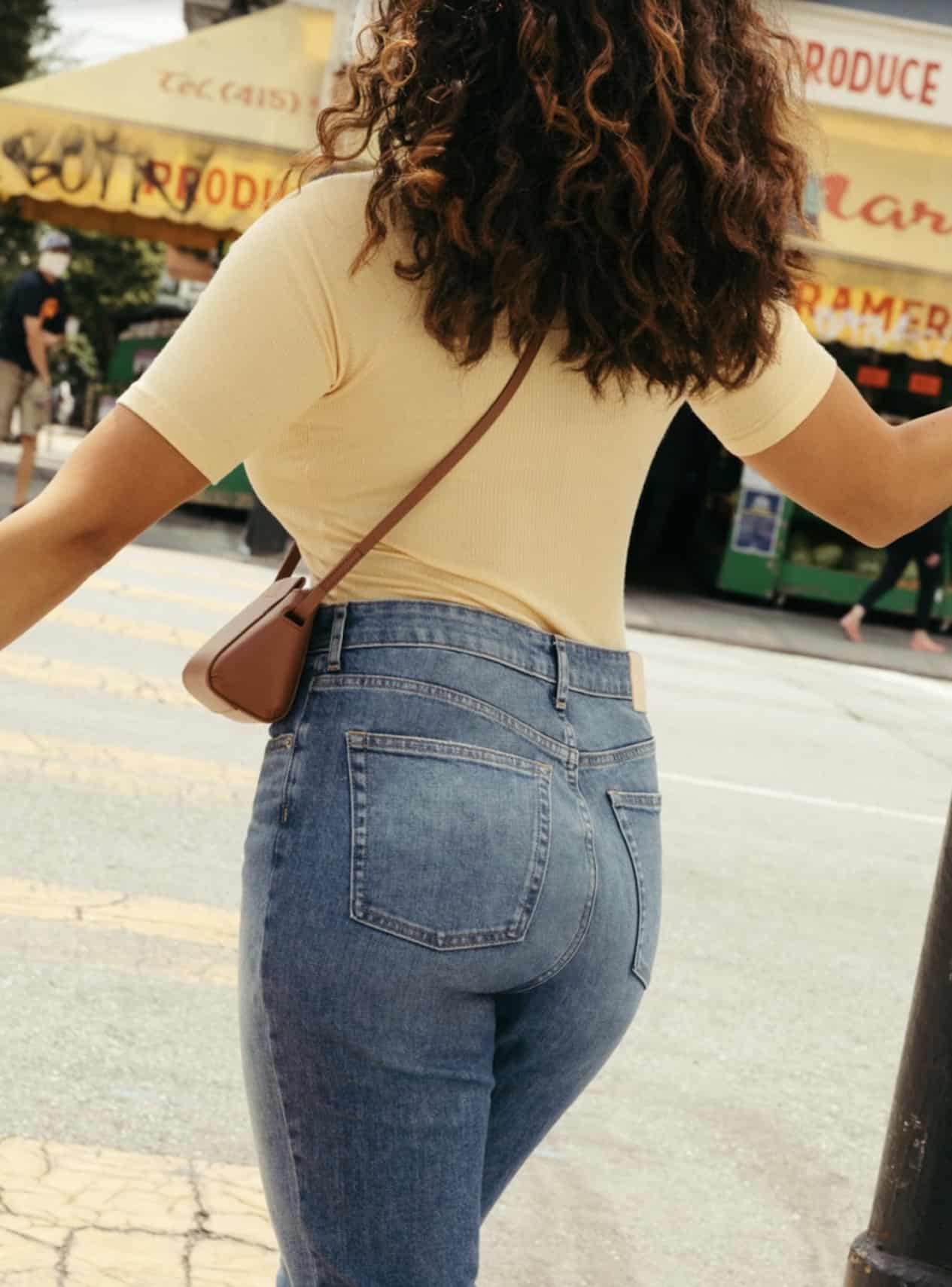Woman wearing light wash jeans and a yellow tee.