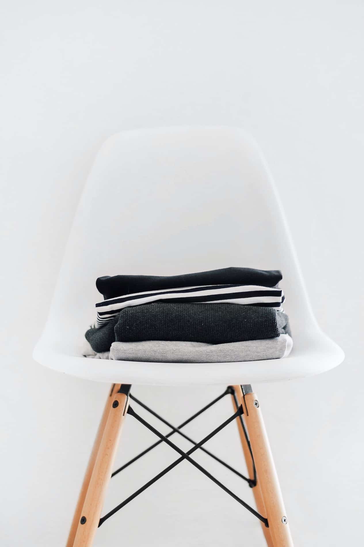Black, white and gray clothing stacked on a white chair.