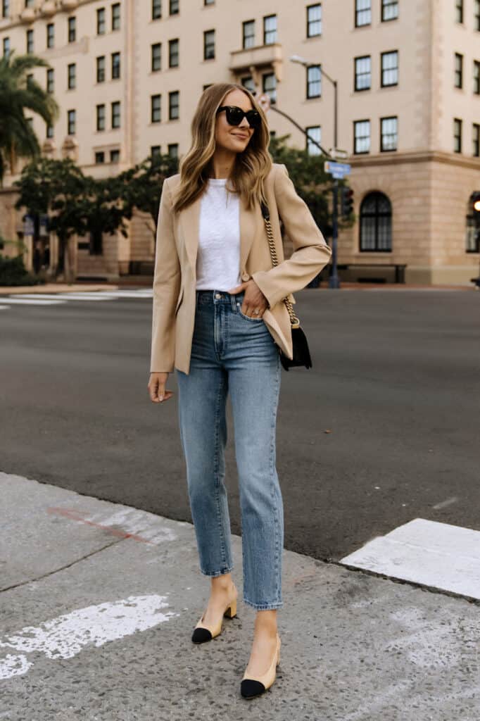 image of a woman standing on the sidewalk wearing a tan blazer, white t-shirt, blue jeans, and Chanel tan pumps