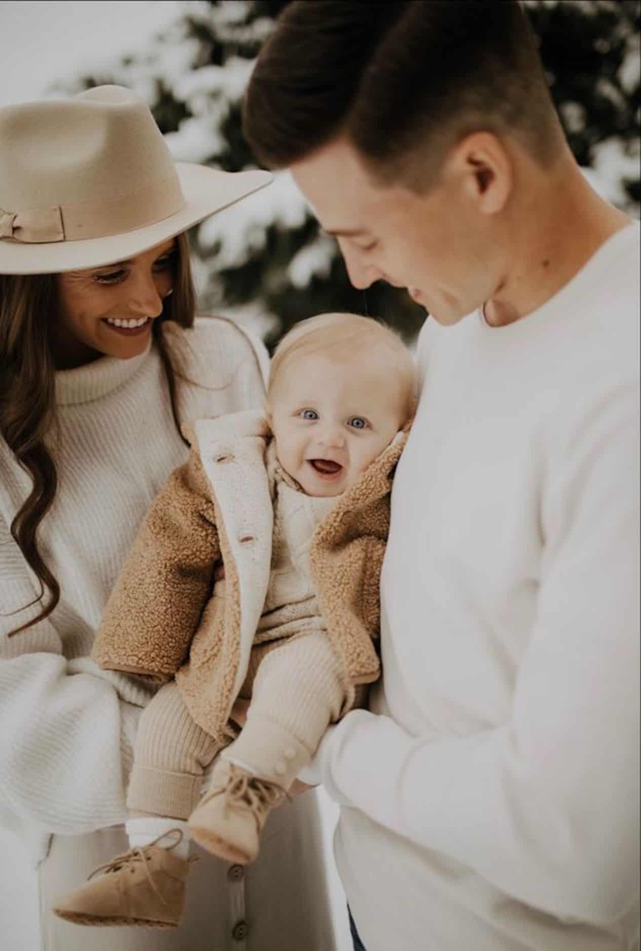 image of a family of three with a mom, dad, and baby all wearing neutral colors in the winter
