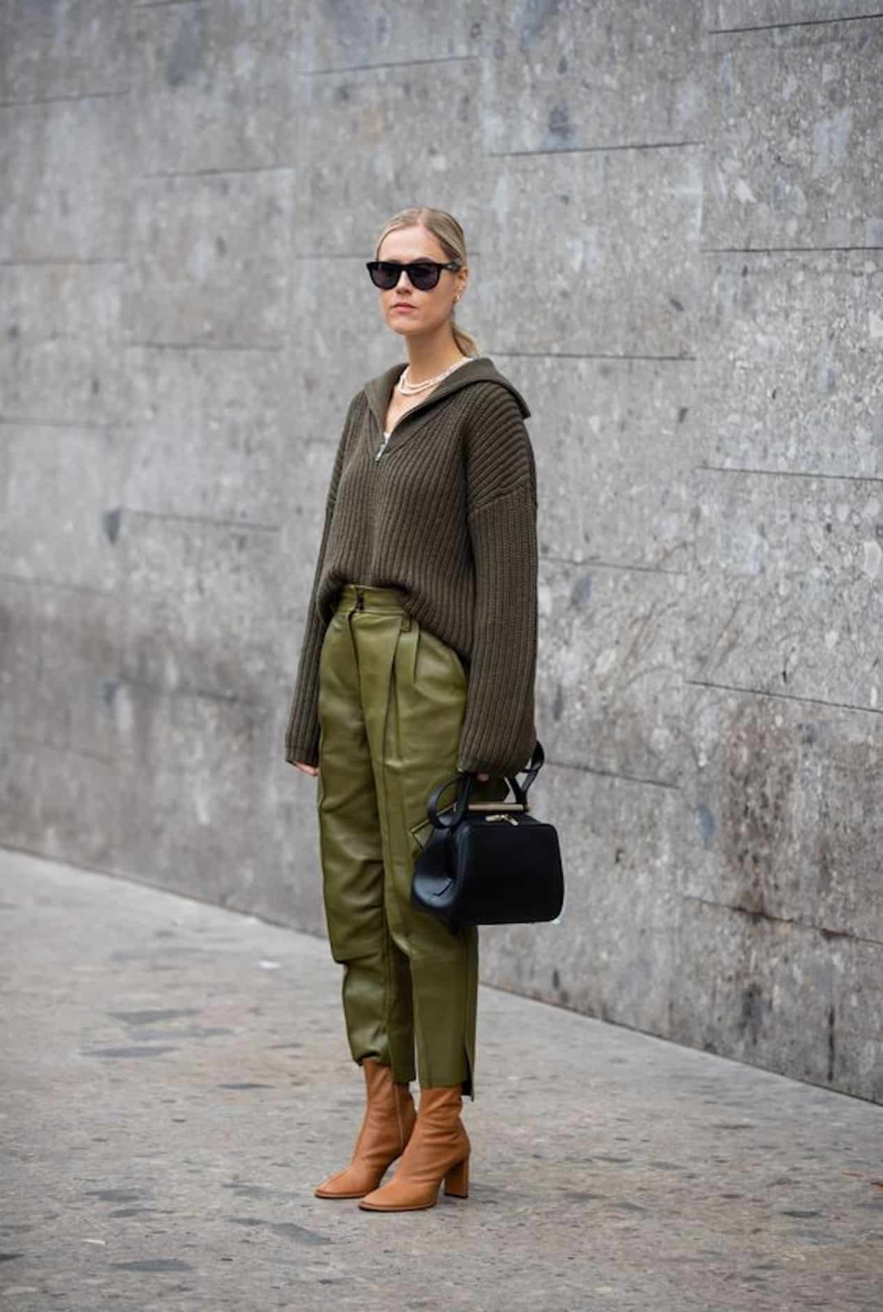 image of a woman standing in front of a grey wall wearing an all green outfit with brown boots