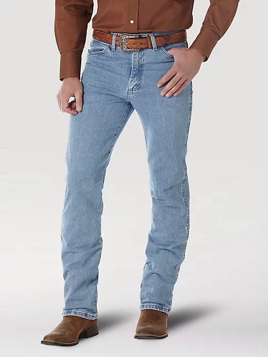 image of a man's legs in light wash slim bootcut jeans and brown boots