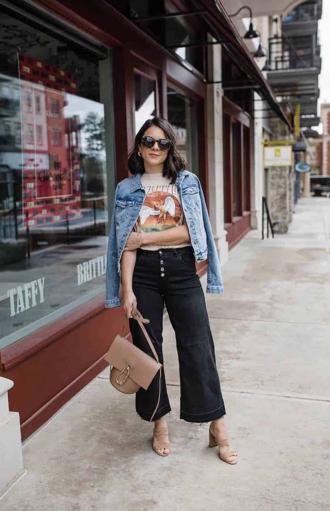 Image of a woman wearing black wide leg jeans and a cropped denim jacket.