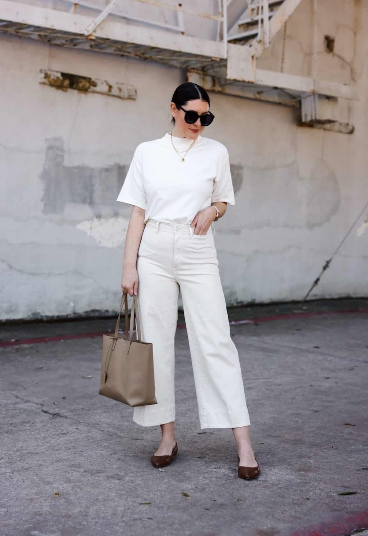 Image of a woman wearing cream wide leg jeans and a plain white tee.