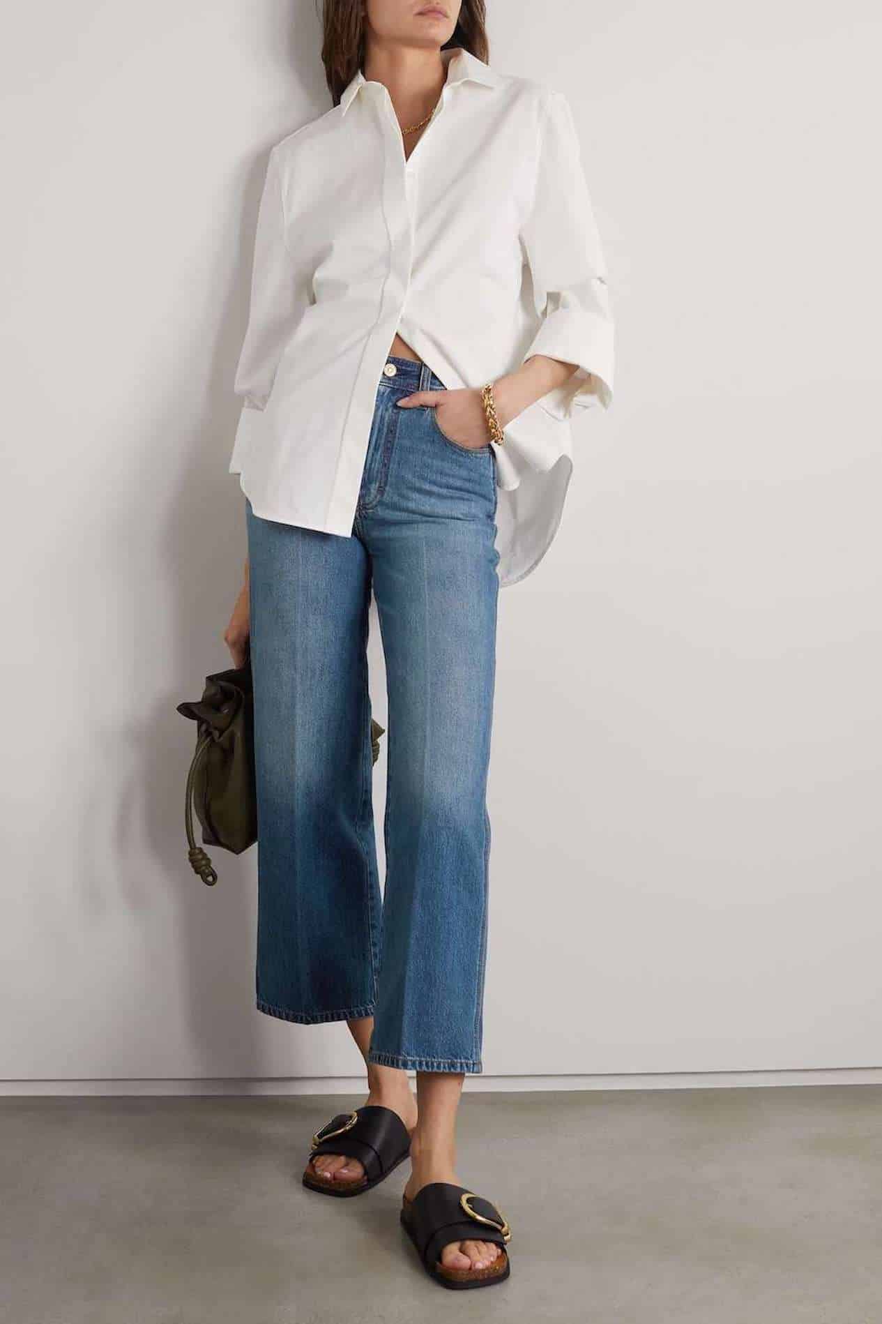 Image of a woman wearing cropped wide leg jeans and a white button down.