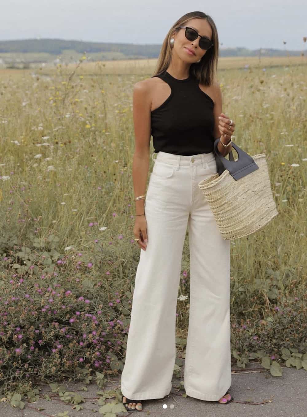 image of a woman in white wide leg jeans and a black tank top with a basket bag