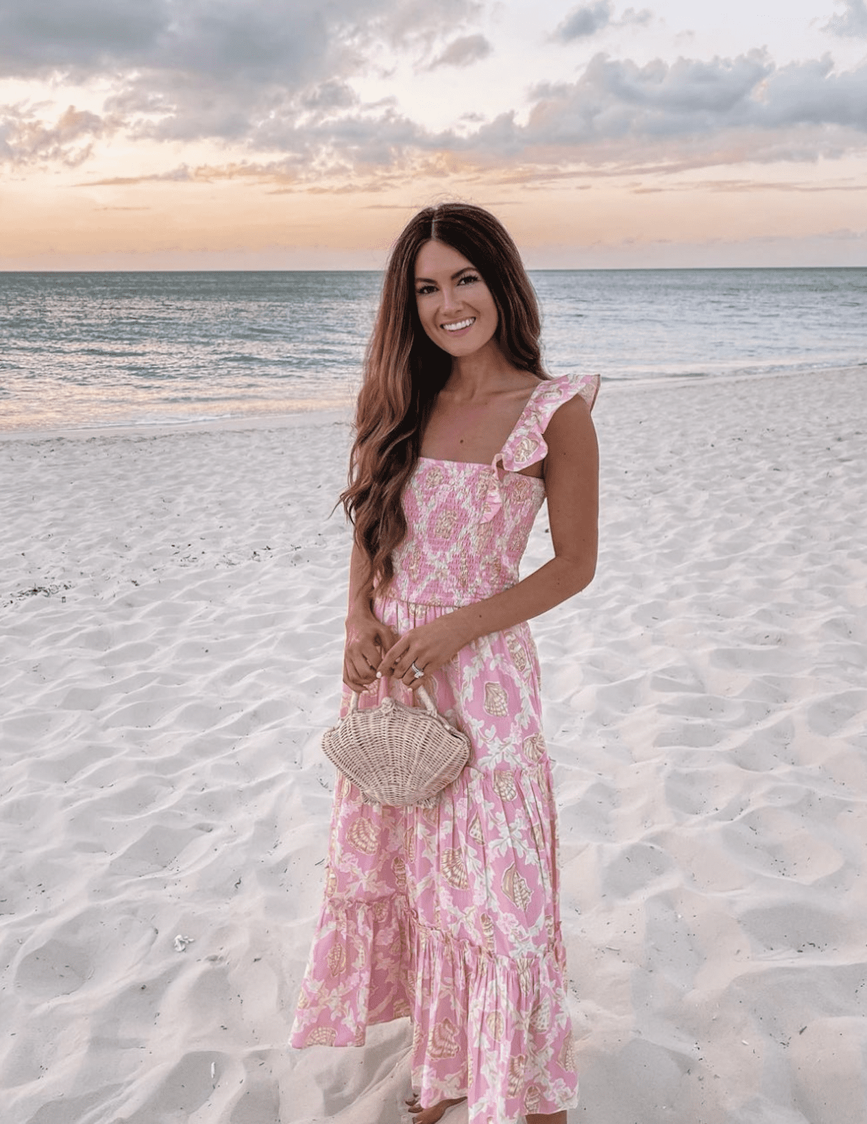 Woman wearing a long, pink maxi dress on the beach.