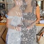 two women wearing floral dresses holding glasses of red wine at a winery with text overlay "what to wear to a winery"