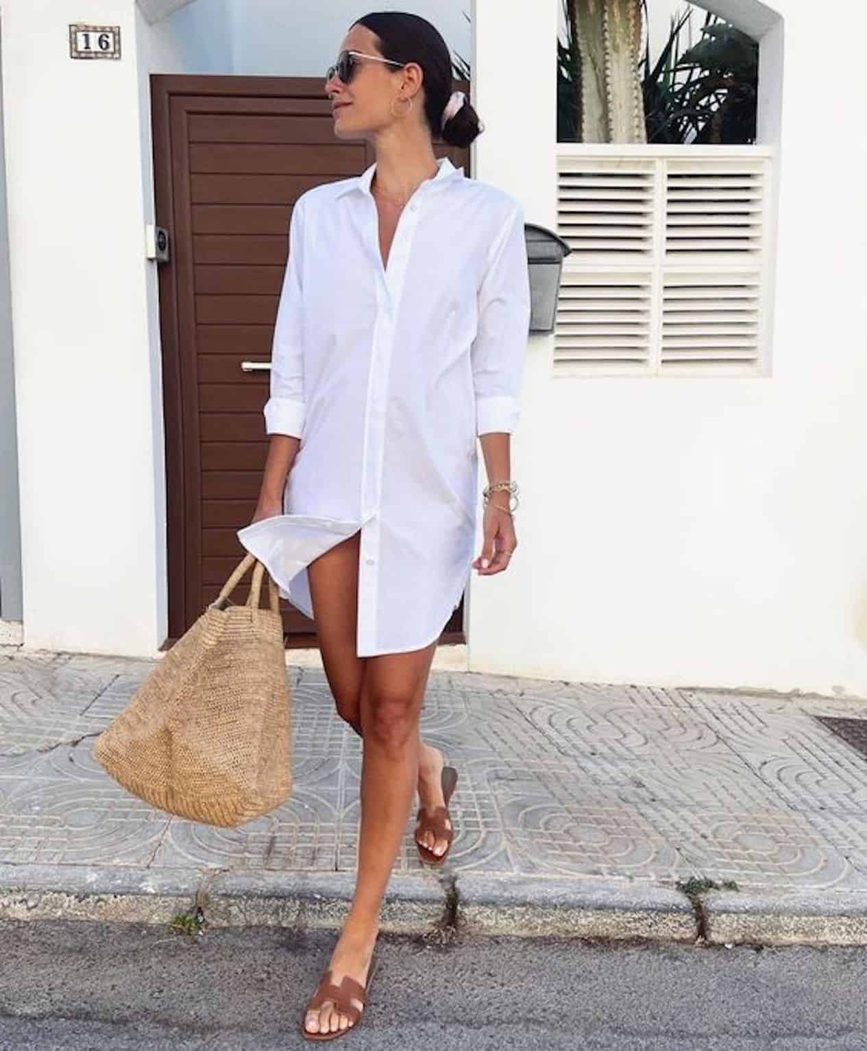 image of a woman crossing the street wearing a white button up shirt dress and brown sandals