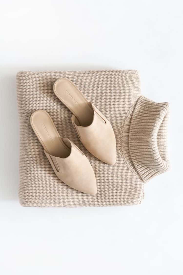 image of a beige knit turtleneck sweater folded with a pair of beige suede mules sitting on top