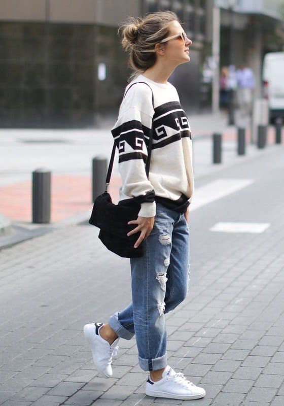 image of a women in boyfriend jeans, sneakers, and a black and white sweater