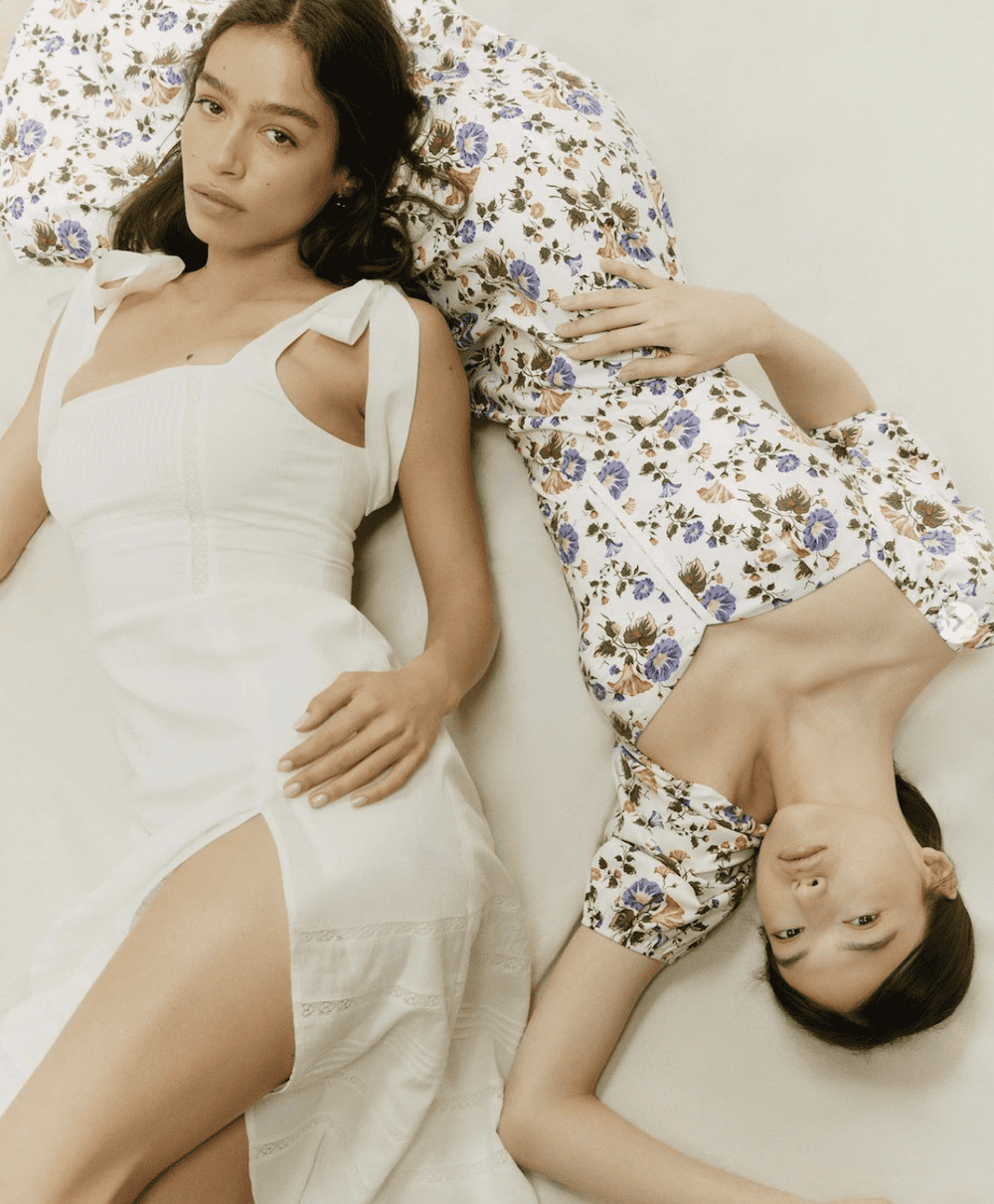 image of two women laying on the ground in pretty floral and white dresses