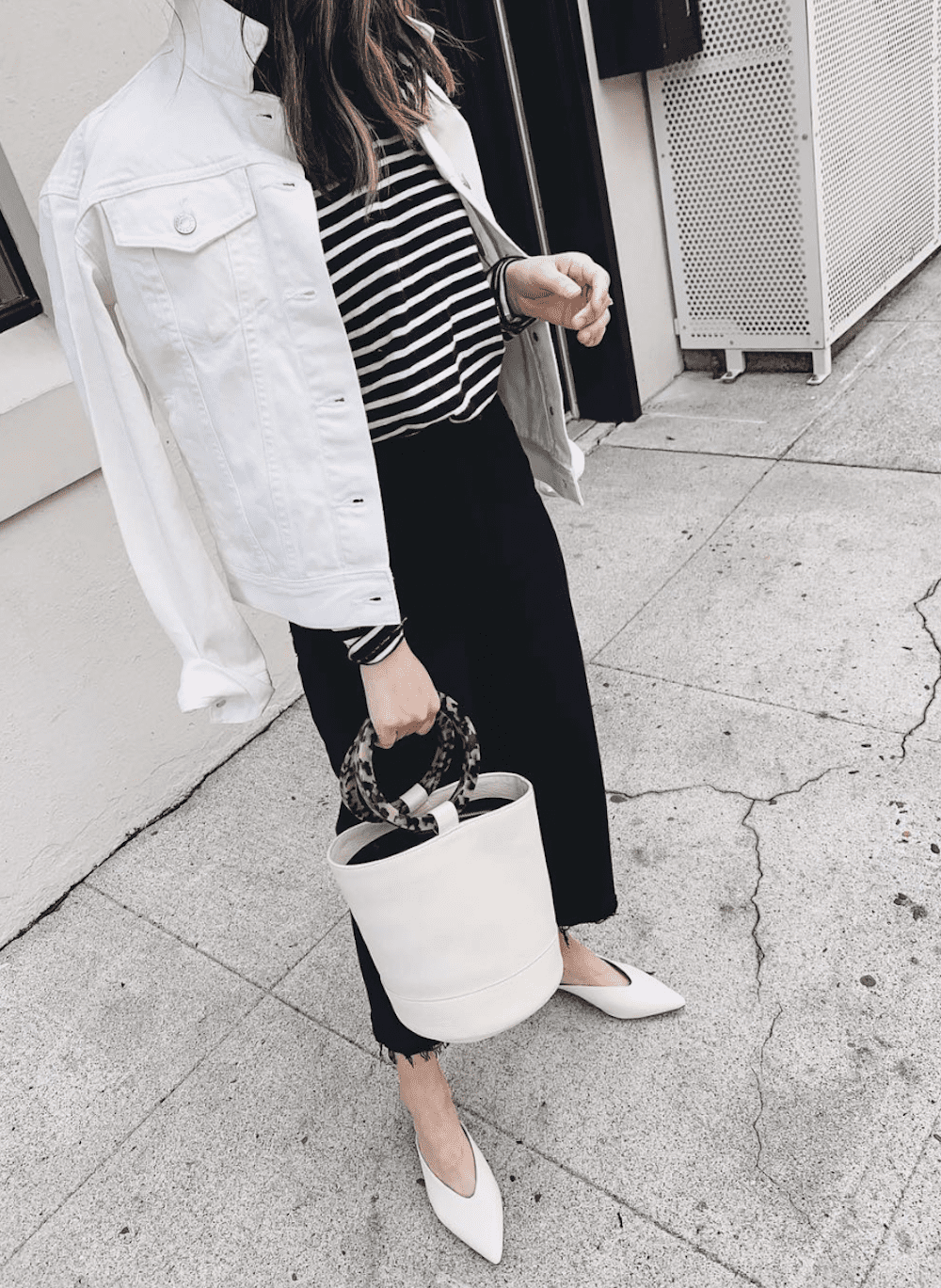 image of a woman in a white jean jacket with striped top and black bottoms