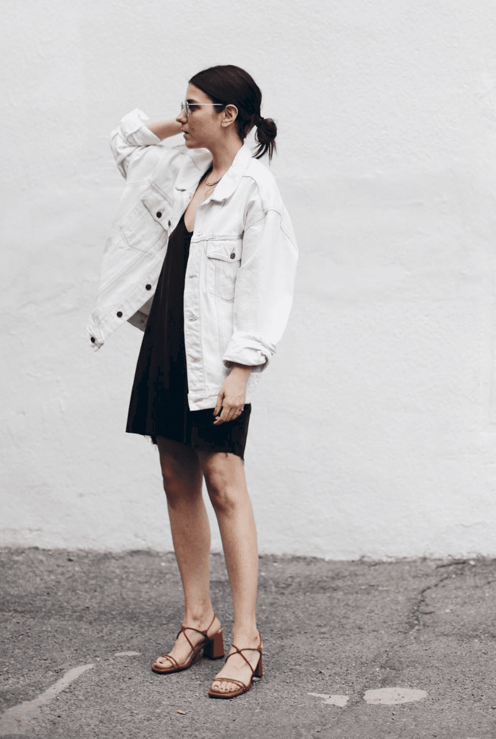 image of a woman in a black short dress and an oversized white denim jacket and red heels