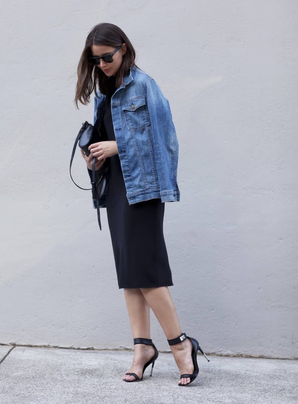 image of a woman in a black dress with a jean jacket over her shoulders and black high heels