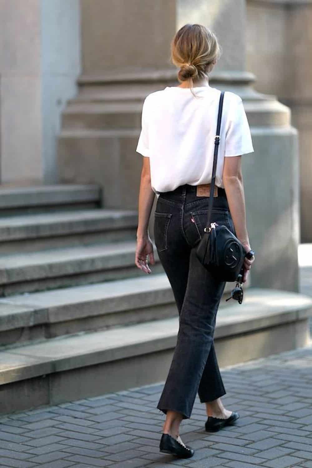 image of a woman from the back walking down the sidewalk in a white t-shirt, black Levi's mom jeans, and black ballet flats