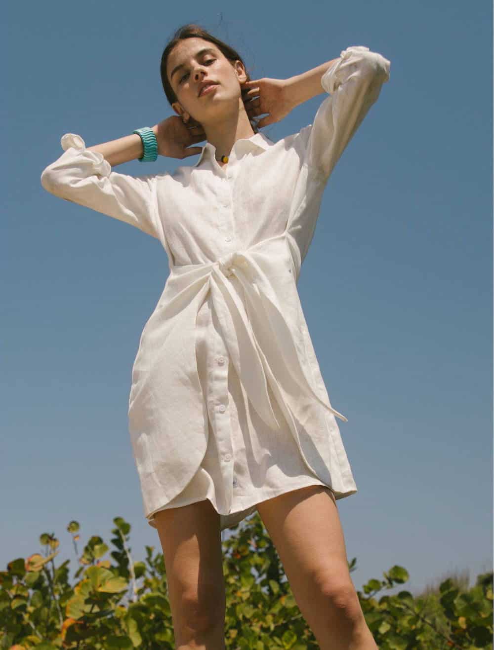 image of a woman standing in front of a blue sky in a white linen shirt dress