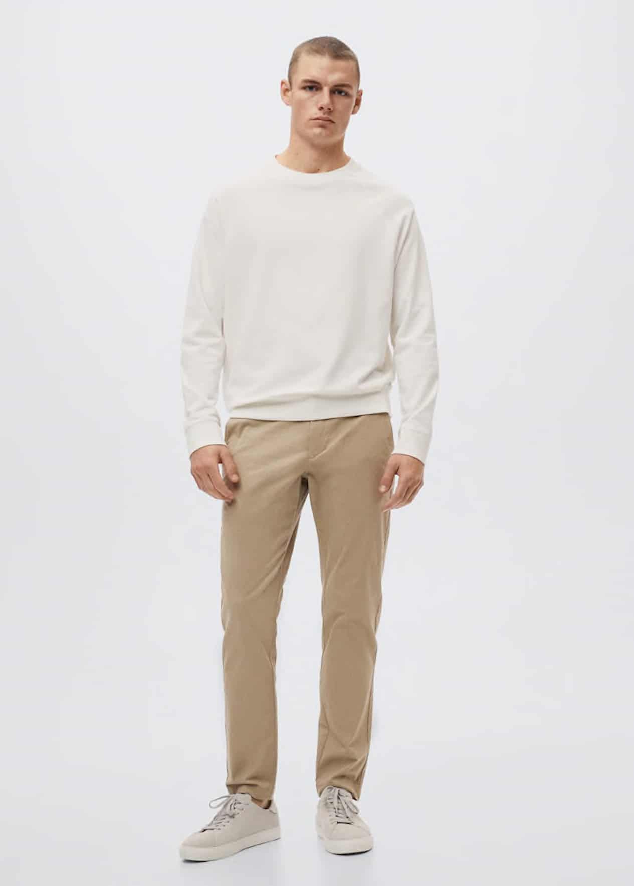 image of a man wearing an ivory sweater, tan khaki pants, and white sneakers