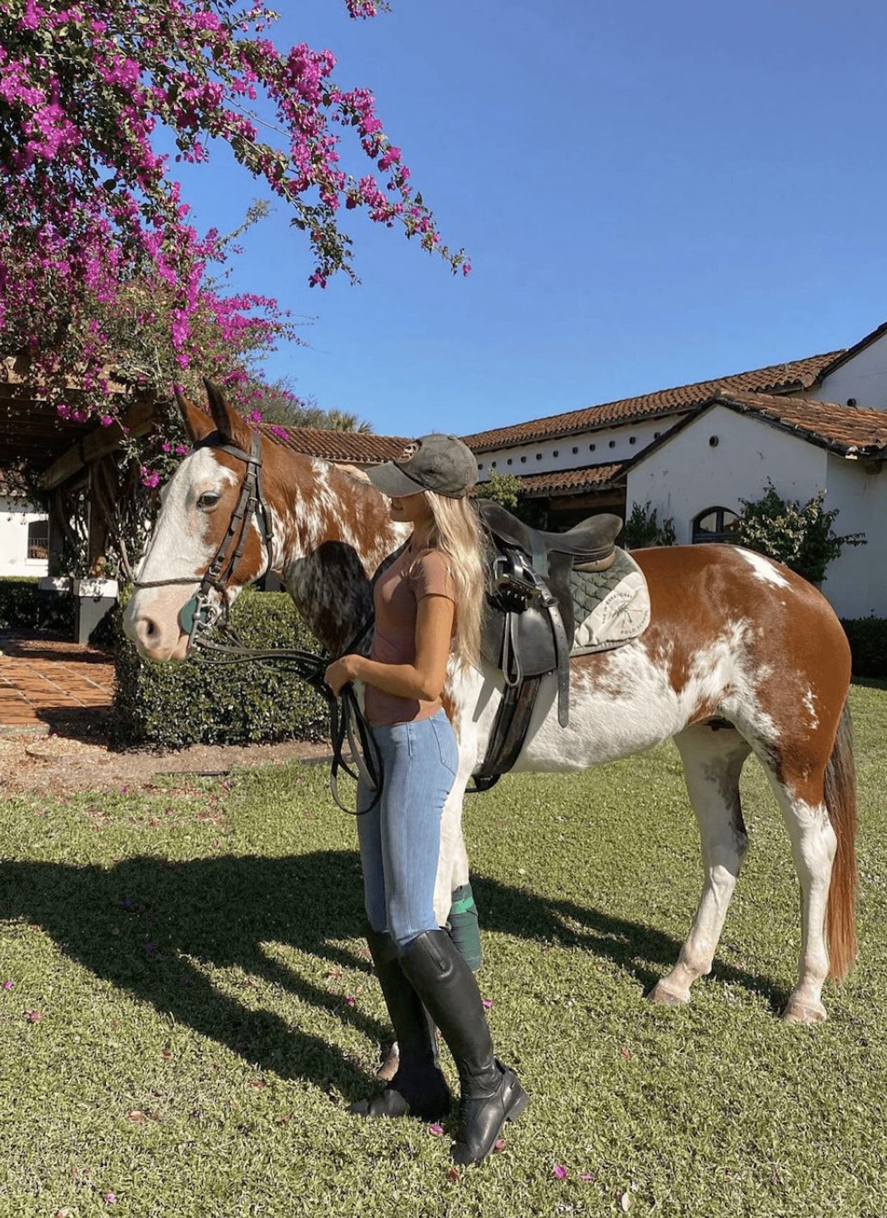 image of a woman standing next to a horse wearing riding boots, jeans, and a t-shirt